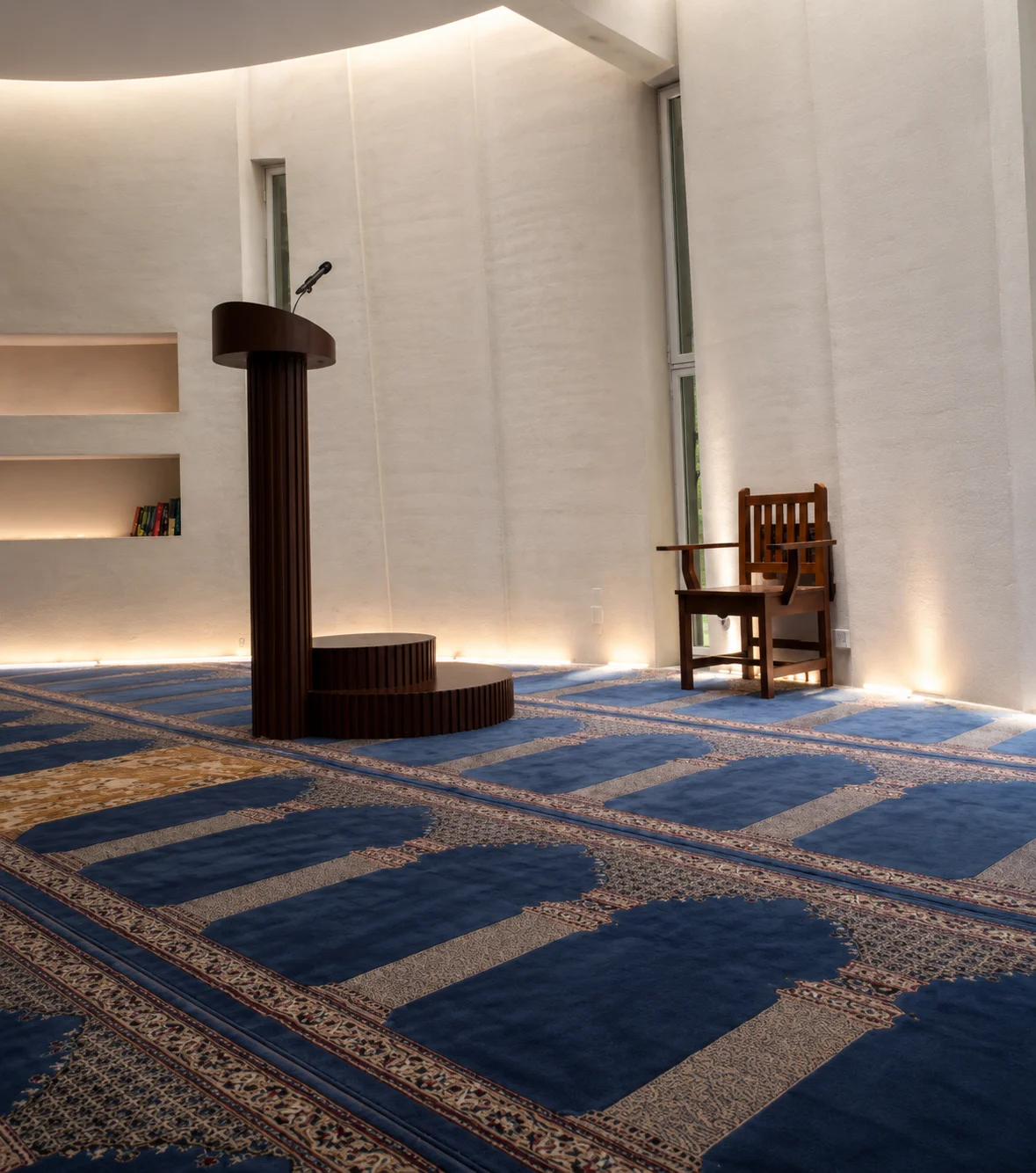 Sala de oración con alfombra azul, minbar y sillas